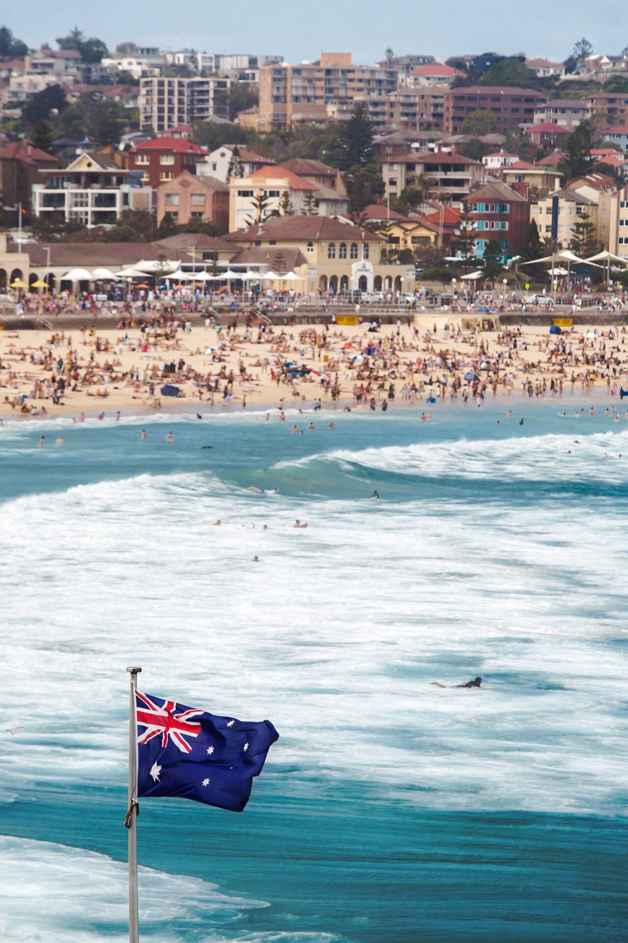 Vertical shot of the Australian flag at the sea in a crowded Bondi beach